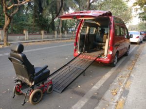 Image shows a Wheelchair Accessible Van with the ramp folded out and a wheelchair at the beginning of the Ramo ready to enter the vehicle.